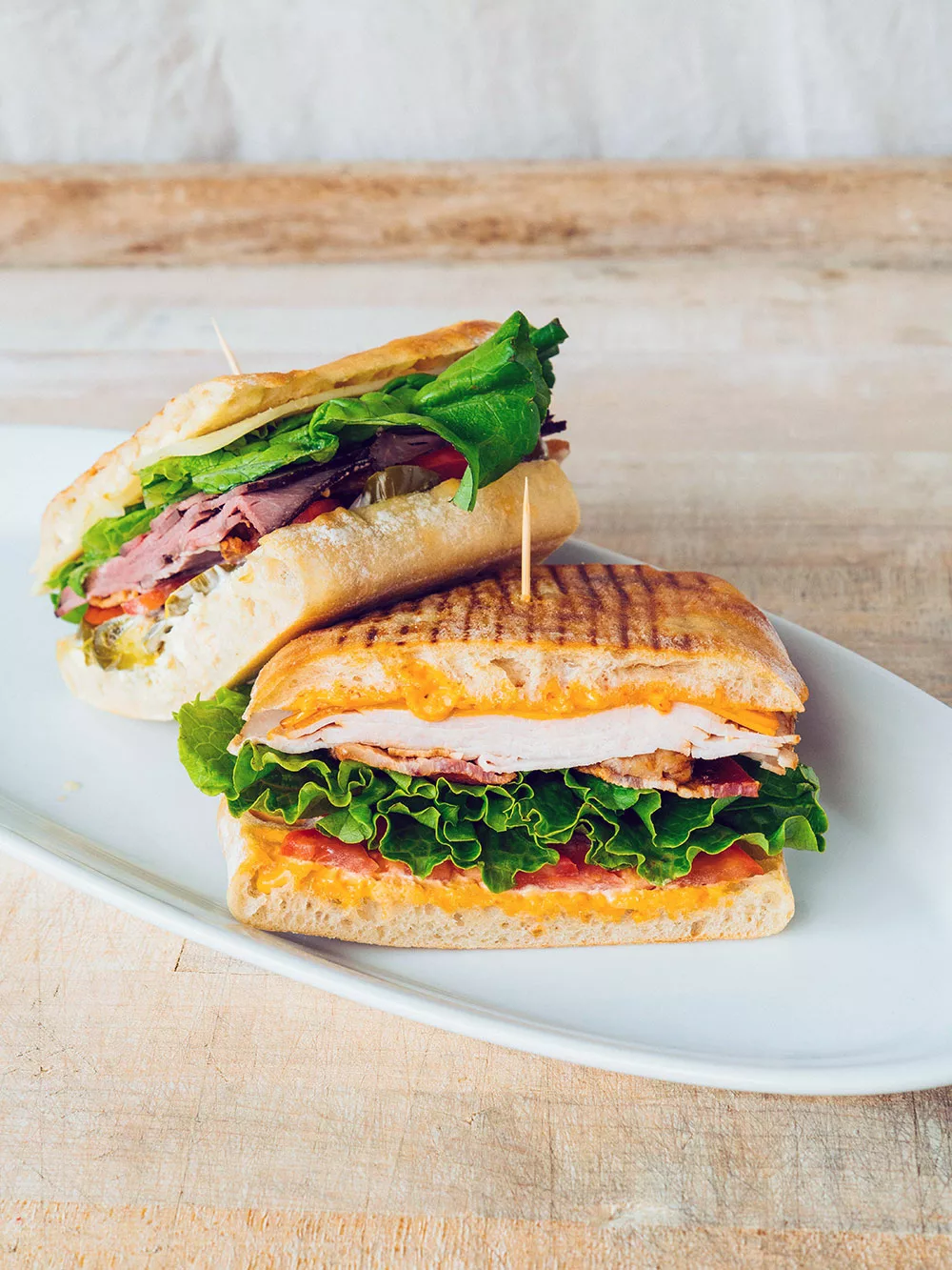 panini sandwich made with bib lettuce, focaccia, bacon, tomato, sliced chicken, and spicy mayo