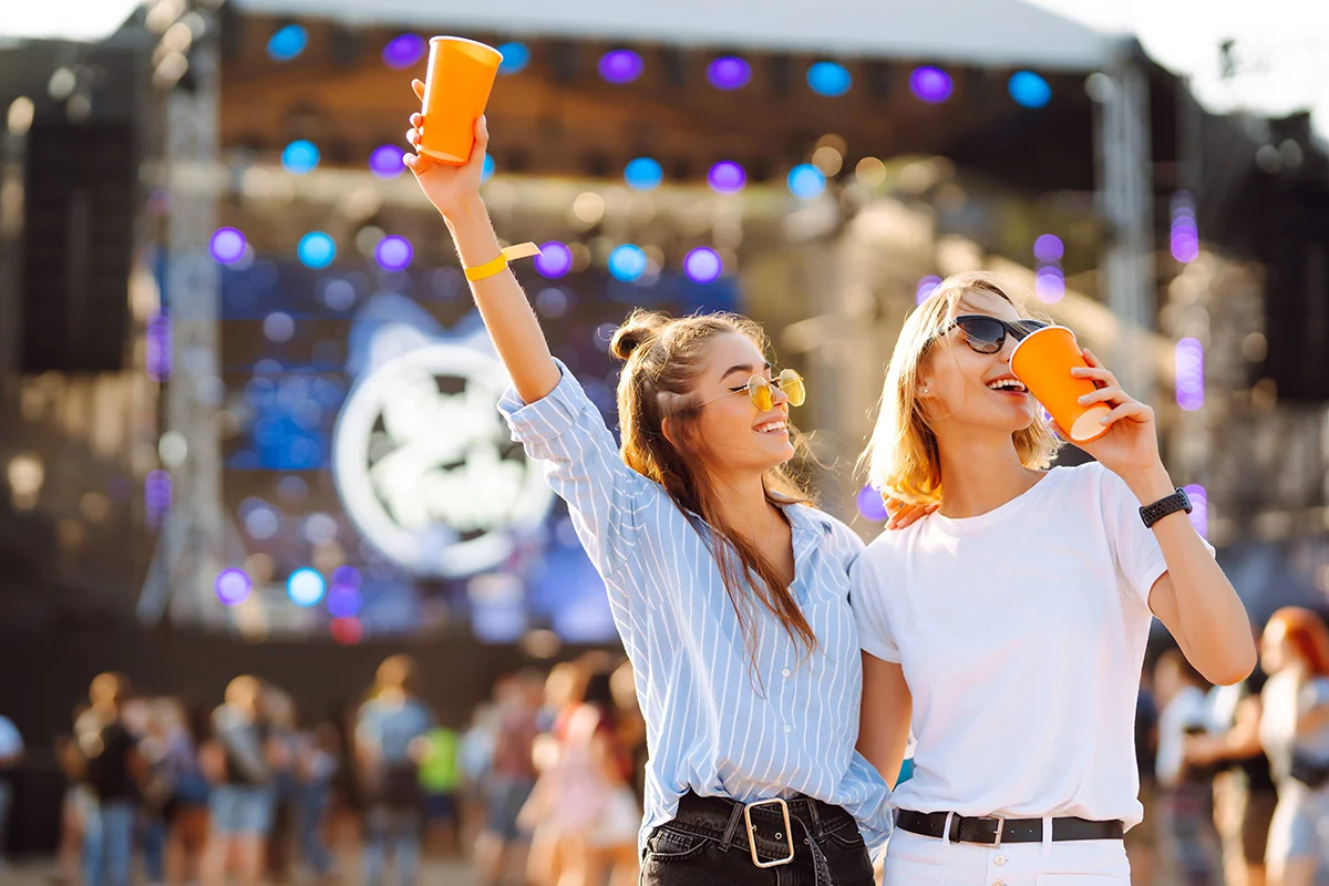 Two young women smiling and holding drinks at BottleRock in Napa
