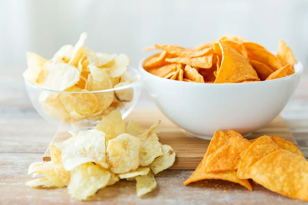 A bowl of potato chips and a bowl of cheesy tortilla chips, showing the concept of quick and easy snacks