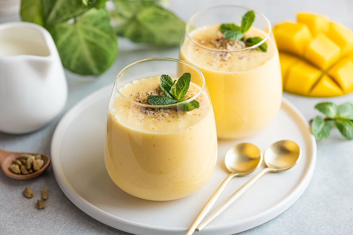 Two glasses of mango rum lassi, garnished with mint