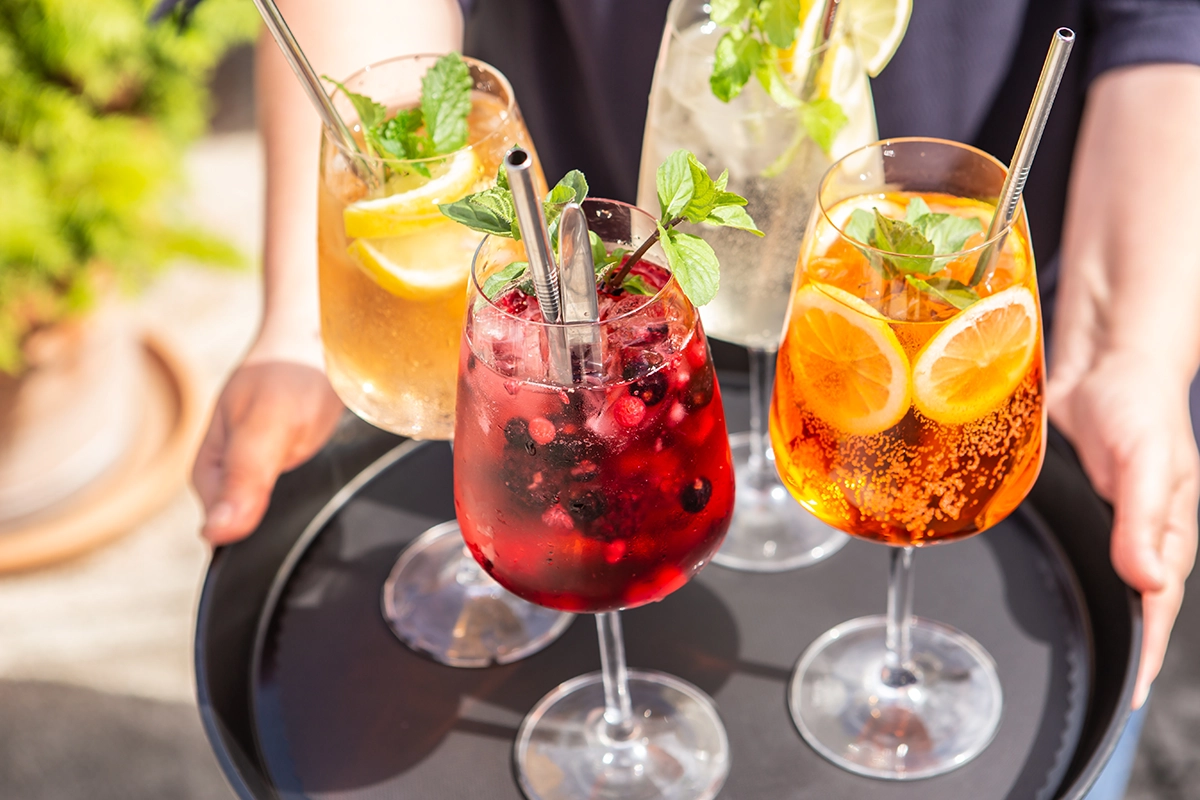 A tray with four summer cocktails garnished with orange and lemon slices
